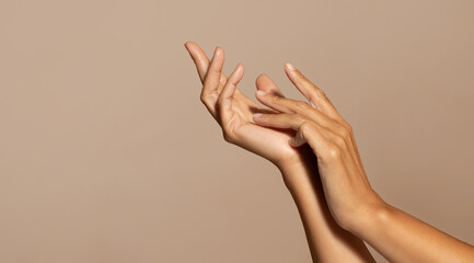 Hands of caucasian senior woman enjoy skin care, isolated on beige studio background, close up