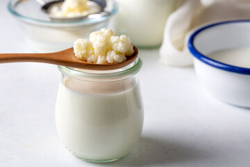 Kefir fermented milk drink with kefir grains. Homemade kefir stands in a glass, next to kefir...