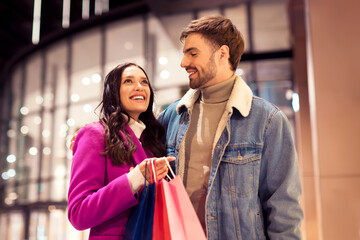 spouses embracing smiling with shopping bags outside of city mall