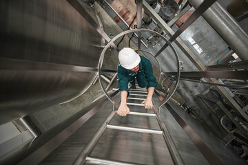 The male worker up the ladder is for inspection stainless steel tank chemical. © chitsanupong