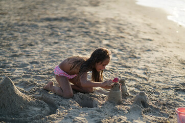 little girl sculpt from sand on the beach