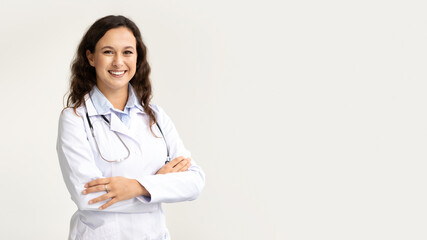 Friendly smiling millennial woman doctor posing isolated on white