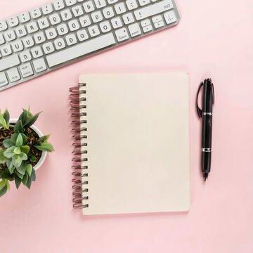 Blank notepad page for text on pink office desktop. Top view of modern bright table with notebook, keyboard