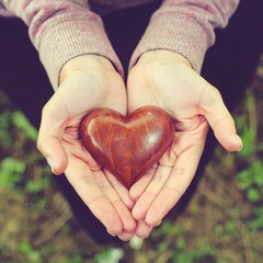 Girl holding wood shape of heart . Concept for giving love
