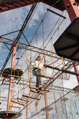 a happy teenage girl passes obstacles in a suspended rope park. the concept of active recreation