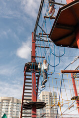 a happy teenage girl passes obstacles in a suspended rope park. the concept of active recreation