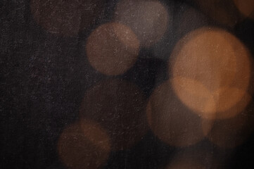 Abstract bokeh texture background with orange and brown circles from a garland on a dark antique backdrop close up. Circles of different sizes, blurred and out of focus.