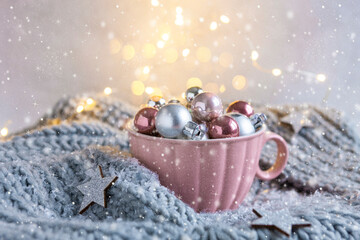 Silver and pink Christmas balls in the big pink mug, grey knitted scarf close up on the snowy and bokeh background - Powered by Adobe
