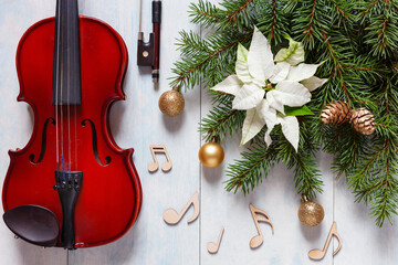 Old violin, wooden notes signs and fir-tree branches with Christmas decor and white poinsettia....