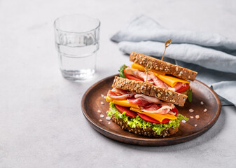 Two toast club sandwiches made of grain bread with cheddar cheese and bacon stuffed with tomatoes...