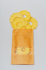 dried pineapple slices in a bag on a white background. dehydrator dried pineapple for cooking and drinking. pineapple chips in a pack on a light background