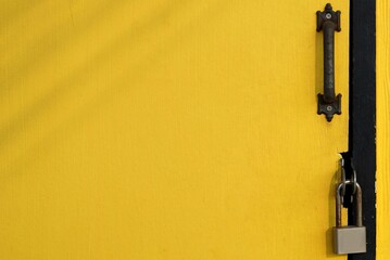 A wooden yellow door with a padlock for background and texture, design small shop concepts.  - obrazy, fototapety, plakaty