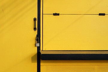 A wooden yellow door with a padlock for background and texture, design small shop concepts. 