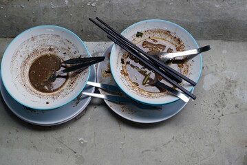 Top view od a dirty dishes with chopsticks in the noodle shop on concrete background. - obrazy, fototapety, plakaty