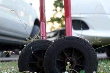 Close up a old black wheel of a barrier traffic with white car backgrounds in the field grass park.