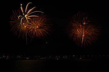 Fireworks explosions with shining sparks on dark background.