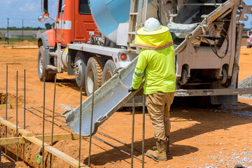 Fototapeta premium Construction worker laying cement pouring concrete in trenches for building house foundation