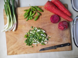 Chopped Green Onions, Chillies, Carrots, and Beetroot with a Knife on a Cutting Board