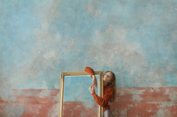 Young girl in knitted sweater leaning on mirror in golden antique frame