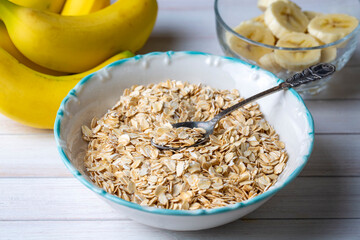 Bowl of oat flakes oatmeal with sliced banana close-up