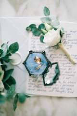 Wedding rings in a glass box lie on the oath next to the boutonniere