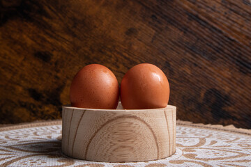 eggs, two eggs placed on a circular wooden container, at the base you can see a mat with mandalas...
