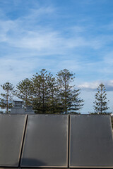 solar panels on the roof of a building, in the background you can see the treetops, vertical photo