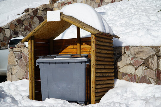 Wooden shelter for trash bins, protecting them from the snow on the street.