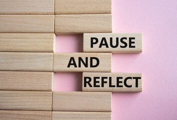 Pause and Reflect symbol. Concept words Pause and Reflect on wooden blocks. Beautiful pink...