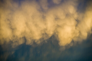 Unusual sunlit fluffy rainclouds in dark blue sky