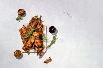 Smoked pork ribs with rosemary on a marble cutting board. light background. Meat for the holiday...