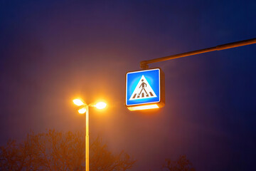 an pedestrian crossing traffic sign at night