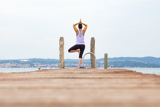 person doing a yoga asanas on a pier at a lake