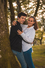 Young couple embracing leaning on a tree