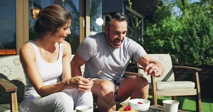 Couple, coffee and happy for breakfast on garden patio with love, care or diet with bonding, relax or morning sunshine. Man, woman and eating food on date, tea cup or vacation with chat in backyard