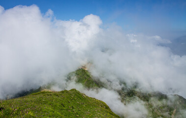 Dramatic landscape - white clouds among the peaks of the mountains against the blue sky on a sunny day and a space to copy