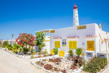 Wonderful houses on Farol island with lighthouse in the back, Portugal - 684311625