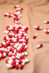 A pile of red and white capsules lying on a cardboard surface.