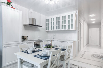 Elegant kitchen interior design. White kitchen set with built-in appliances. A dining .table with a beautiful setting.