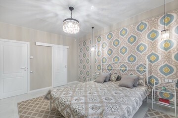 Modern bedroom design. Double metal bed with a bedspread and pillows. Wallpaper with a pattern,...