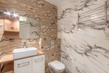 Bathroom decorated with tiles of different colors with the effect of natural stone. .A mirror with...