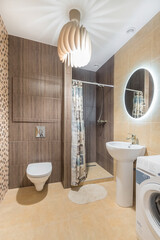 Bathroom with toilet, shower behind a curtain and a small sink. The room is decorated with various...
