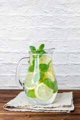 Lemonade with mint in jug on wooden table