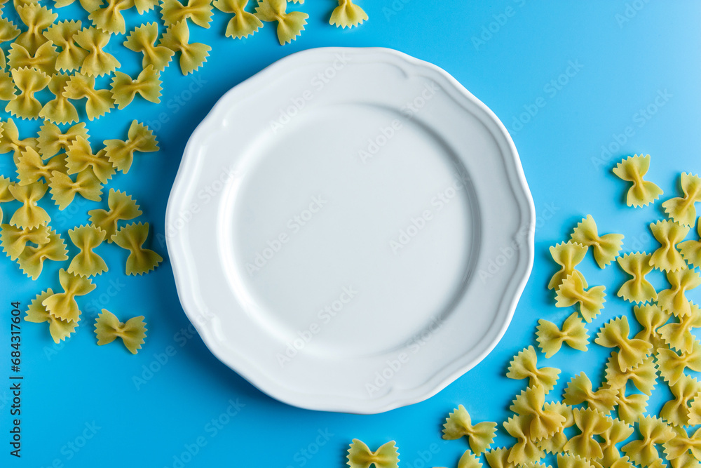 Wall mural raw pasta farfalle with copy space on blue background