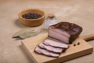 Smoked brisket, cut into slices. Nearby spices lie on a beige background