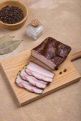 Smoked brisket, cut into slices. Nearby spices lie on a beige background