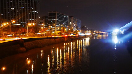 Promenade au bord de la Seine, pendant une soirée nocturne, réflexion lampadaire jaune et orange sur l'eau, animation et circulation urbaine, calme, froid et tranquille, hiver Paris, soirée agitée, 