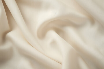 Obraz premium Light beige colour satin cloth folds abstract closeup background. Silk fabric tissue curves