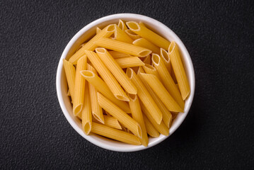 Raw penne pasta from whole grain wheat varieties with salt and spices