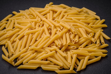 Raw penne pasta from whole grain wheat varieties with salt and spices